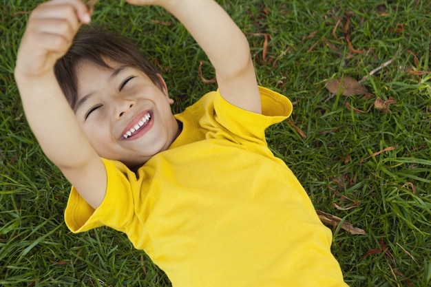 Jeune garçon couché sur l&#39;herbe au parc