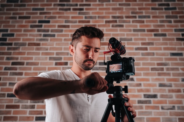 Jeune garçon dans la vingtaine ajustant le trépied de l'appareil photo dans son studio