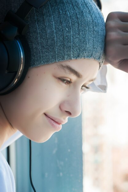 Un Jeune Garçon écoutant De La Musique Tout En Regardant Par La Fenêtre