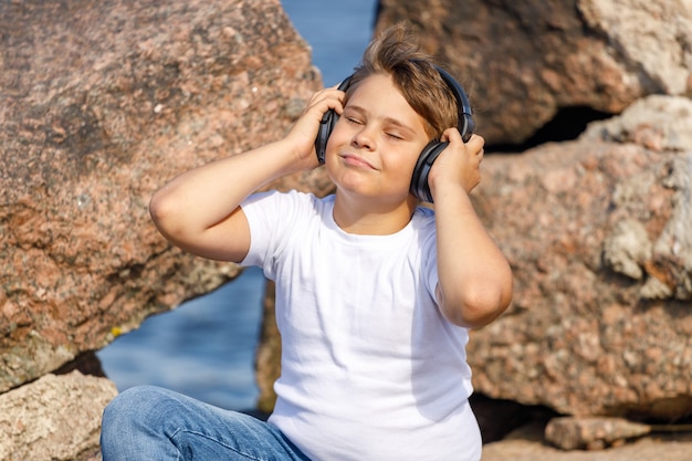 Jeune garçon avec des écouteurs écoutant de la musique à l'extérieur