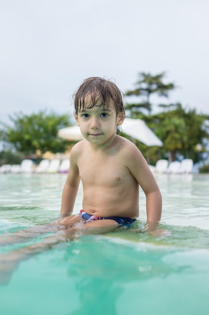 Jeune garçon enfant enfant éclaboussant dans la piscine s'amusant activité de loisirs