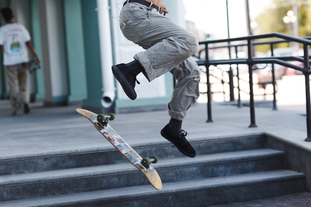 Jeune garçon équitation trick sur skateboard en ville.