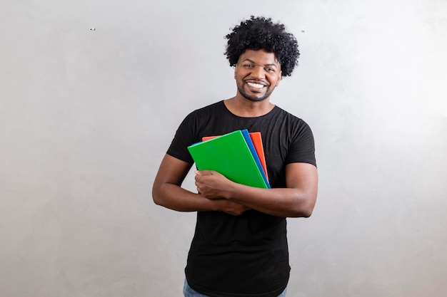 Jeune garçon étudiant noir avec des livres et des cahiers sur fond