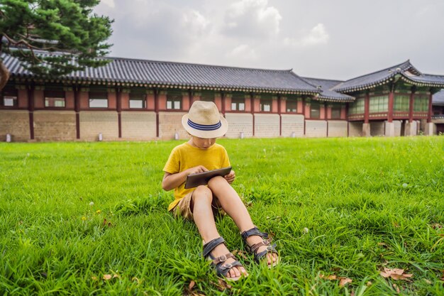 Jeune garçon à l'extérieur sur l'herbe à l'arrière-cour à l'aide de son ordinateur tablette Éduquer et jouer