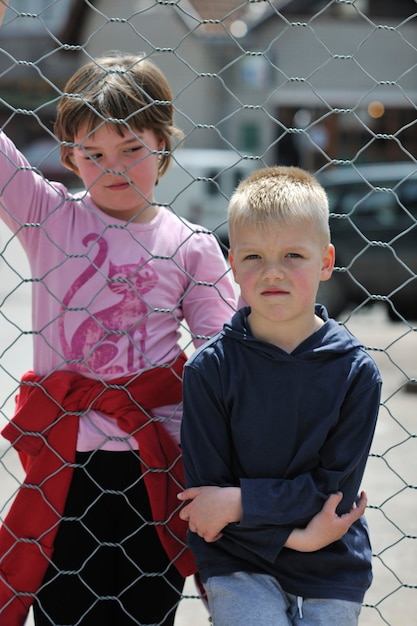 jeune garçon et fille debout sur une clôture de fer le jour et représentant le concept urbain et de mode pour enfant