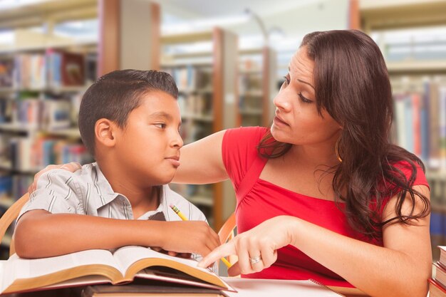 Un jeune garçon hispanique et une famille d'adultes étudient à la bibliothèque