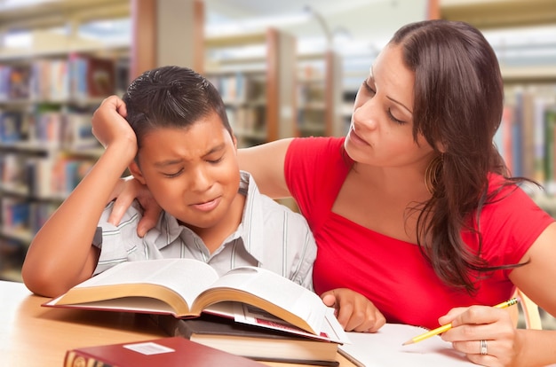 Un jeune garçon hispanique et sa famille étudient à la bibliothèque.