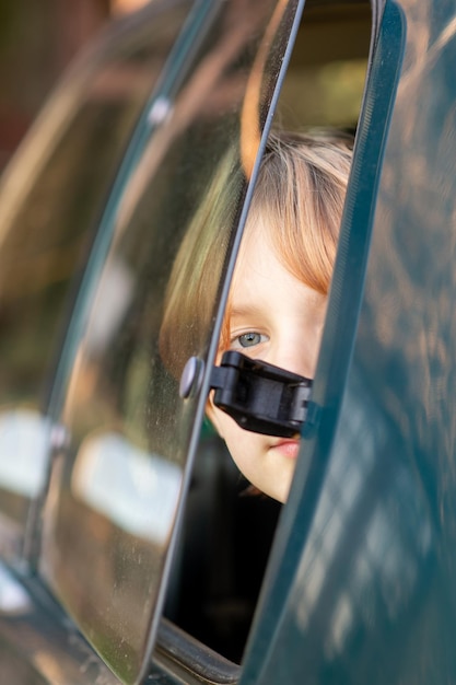 Photo un jeune garçon de huit ou dix ans est assis dans une voiture devant le verre semi-ouvert concept de train de voyage en voiture garçon roux stuffiness in the car airing