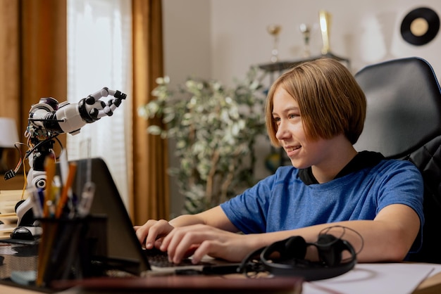 Jeune garçon intelligent faisant ses devoirs dans un cahier d'exercices sur un ordinateur portable