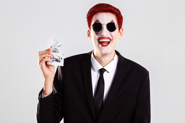 Photo un jeune garçon avec un joker maquillage artistique. concept de jeu et de casino. tourné en studio. fond blanc .