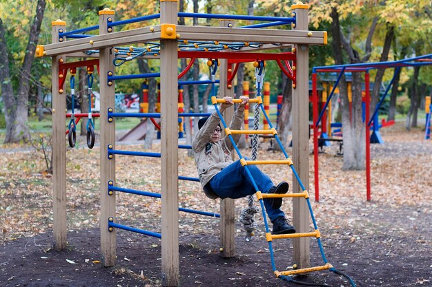 Jeune garçon jouant sur l'aire de jeux dans le parc en automne