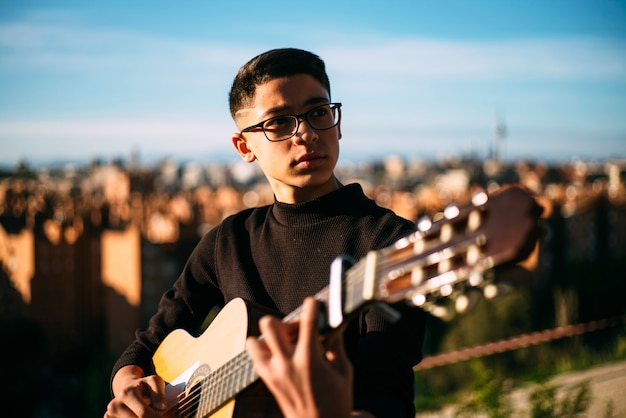 Jeune garçon jouant de la guitare dans la ville de Madrid, Espagne en arrière-plan.