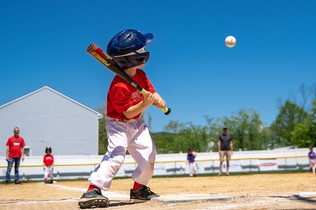 Photo un jeune garçon joue au baseball et le batteur porte un maillot rouge