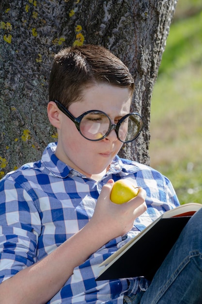 Jeune garçon lisant un livre dans les bois avec une faible profondeur de champ et un espace de copie