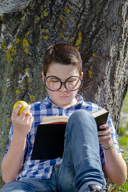 Jeune garçon lisant un livre dans les bois avec une faible profondeur de champ et un espace de copie