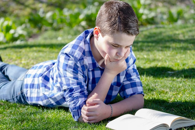 Jeune garçon lisant un livre dans les bois avec une faible profondeur de champ et un espace de copie