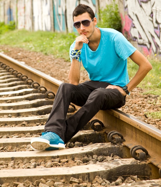 Jeune garçon à lunettes assis au chemin de fer.