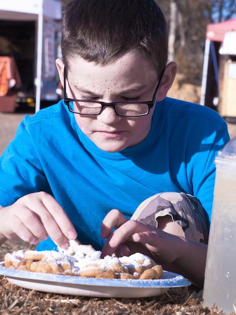 Jeune garçon mangeant un gâteau en entonnoir.