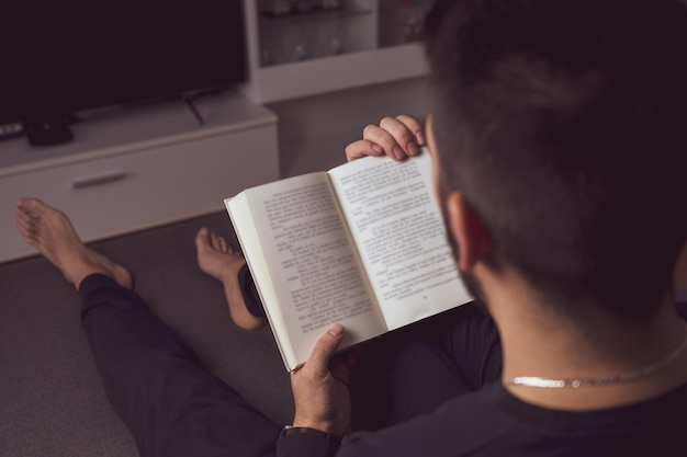 Jeune garçon méconnaissable lisant un livre dans sa maison