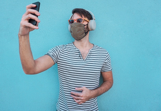 Jeune garçon prenant selfie avec masque et lunettes de soleil