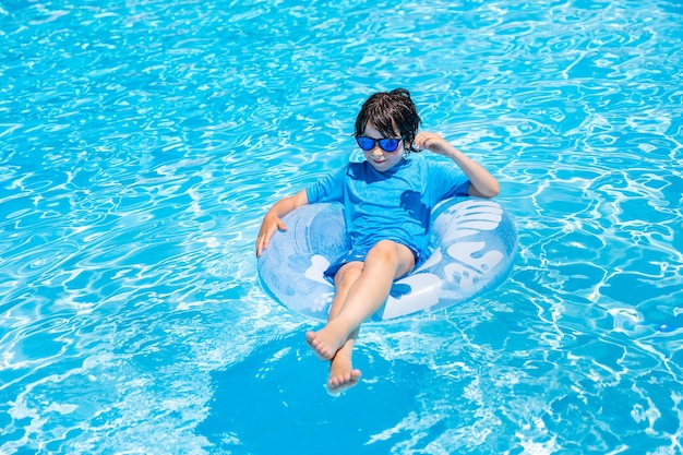 jeune garçon reposant sur un anneau gonflable dans la piscine en été.