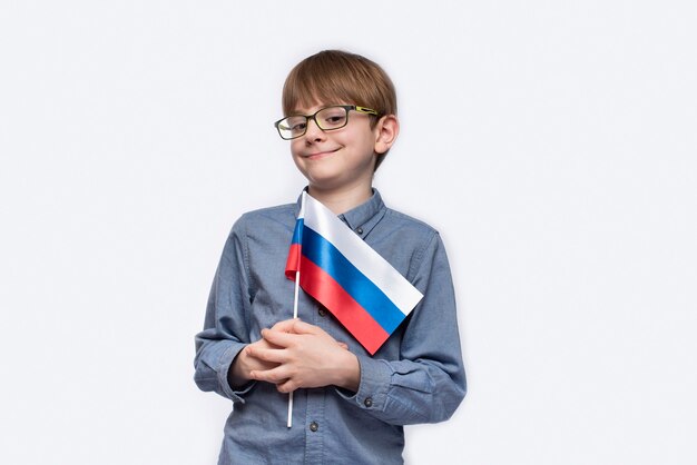 Jeune garçon restant et prenant le drapeau de la Russie à la main. Jour de la Russie.