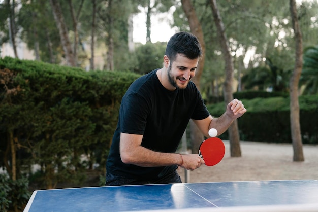 Jeune garçon s'entraînant au ping-pong à l'extérieur dans un débardeur