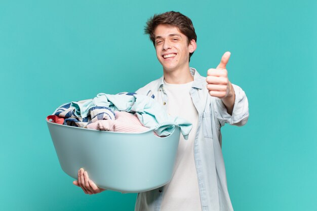 Jeune garçon se sentant fier, insouciant, confiant et heureux, souriant positivement avec le pouce levé concept de vêtements de lavage