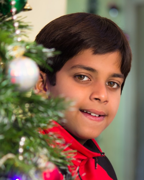 Un jeune garçon souriant de l'arbre de Noël