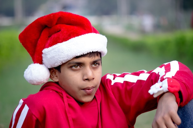 Un jeune garçon souriant attirant heureux dans le chapeau de Santa, regardant à une distance