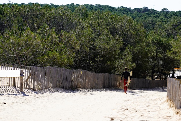 Jeune garçon surfeur sur le chemin de la plage vu de dos