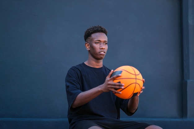 jeune garçon, tenue, basket-ball, à, arrière-plan noir