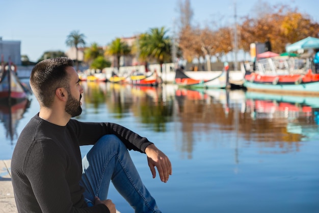 Jeune garçon touriste assis près d'un canal d'eau à Aveiro Portugal