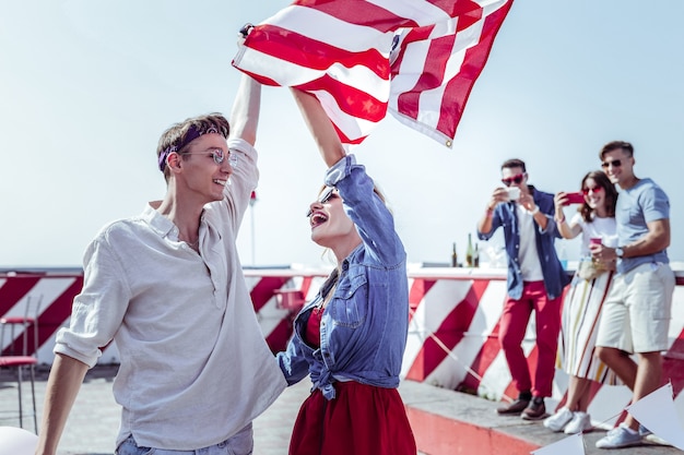 Photo jeune génération. beau mâle main levée tout en tenant le drapeau américain