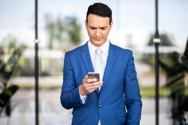 Jeune gestionnaire à l'aide d'un smartphone numérique en plein air