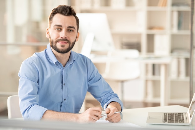 Jeune gestionnaire de bureau élégant ou consultant assis au bureau