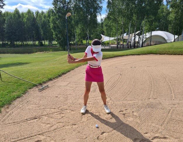 Une jeune golfeuse lance une balle de golf dans un bunker de sable