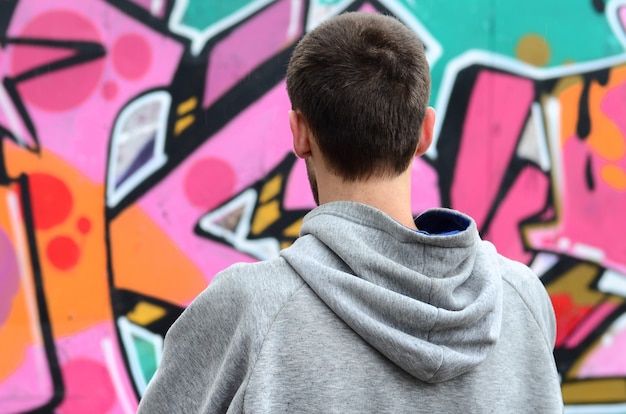 Une Jeune Graffeuse En Sweat à Capuche Gris Regarde Le Mur Avec