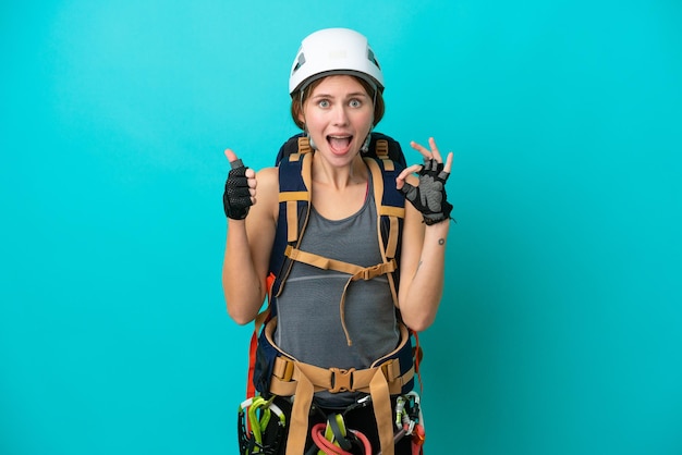 Jeune grimpeur anglais femme isolée sur fond bleu montrant le signe ok et le geste du pouce vers le haut