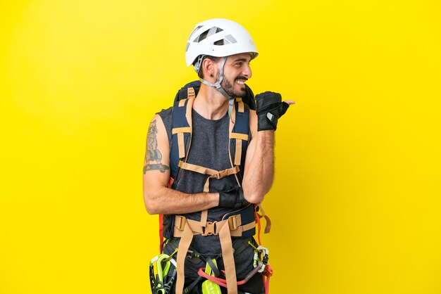 Jeune grimpeur caucasien isolé sur fond jaune pointant vers le côté pour présenter un produit