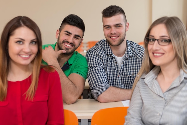 Photo jeune groupe d'étudiants adolescents attrayants dans une classe de collège assis à une table des leçons d'apprentissage