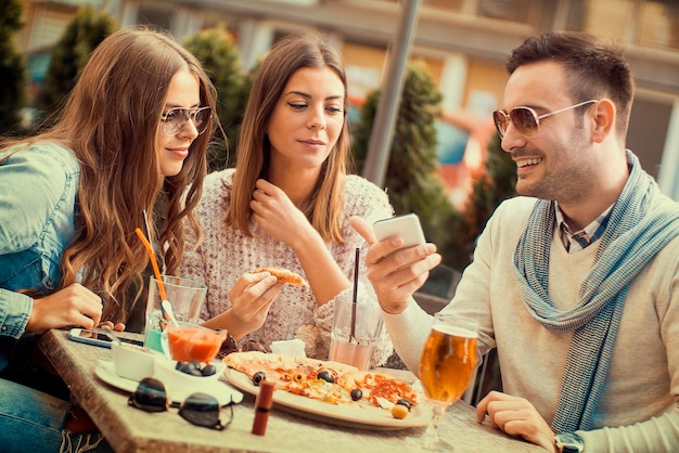 Jeune groupe de gens qui rient en train de manger de la pizza et de s'amuser