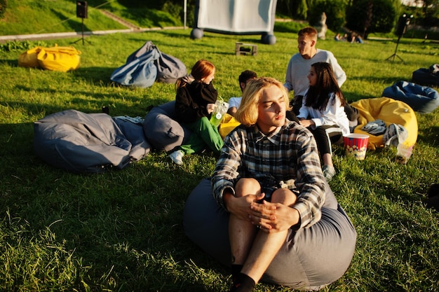 Jeune groupe multiethnique de personnes regardant un film au pouf dans un cinéma en plein air