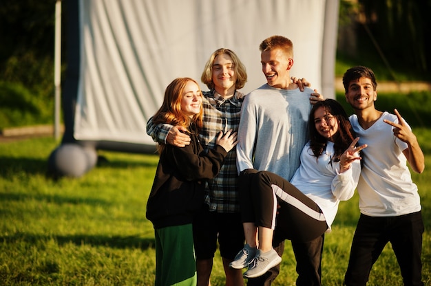 Jeune groupe multiethnique de personnes regardant un film à pouf dans un cinéma en plein air.