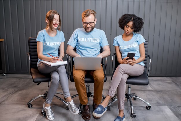 Jeune groupe multiethnique de volontaires en t-shirts bleus travaillant ensemble au bureau