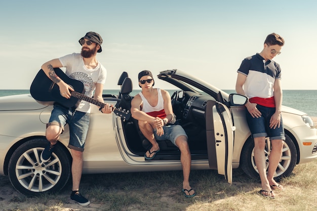 Jeune groupe s&#39;amuser sur la plage, jouer de la guitare