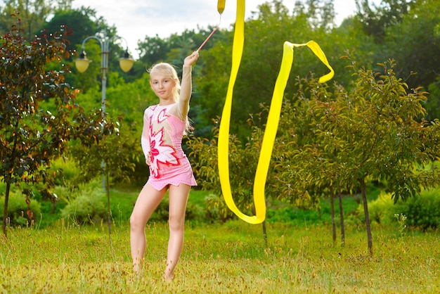 Jeune gymnaste s'échauffe avec un ruban de gymnastique ou une alimentation