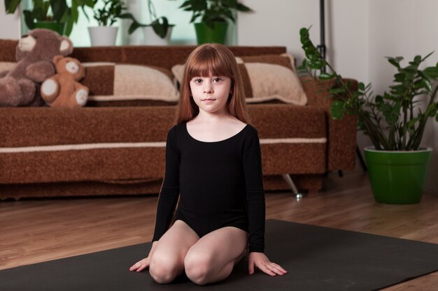 Jeune gymnaste sur le tapis à la maison