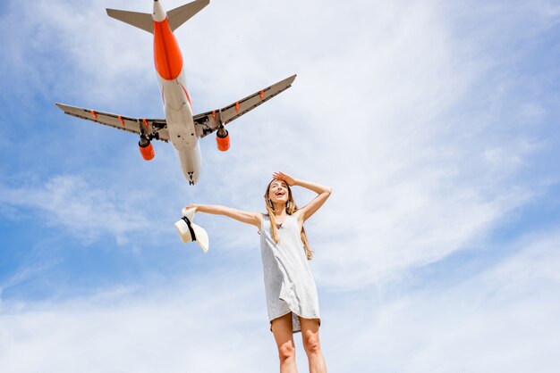 Jeune et heureuse femme appréciant l'avion volant dans le ciel