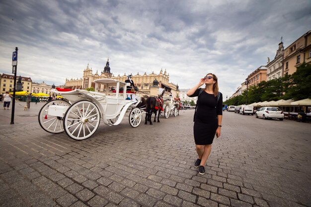 Jeune et heureuse femme touriste marchant sur la place du marché dans la vieille ville européenne Cracovie Pologne voyages à travers l'Europe